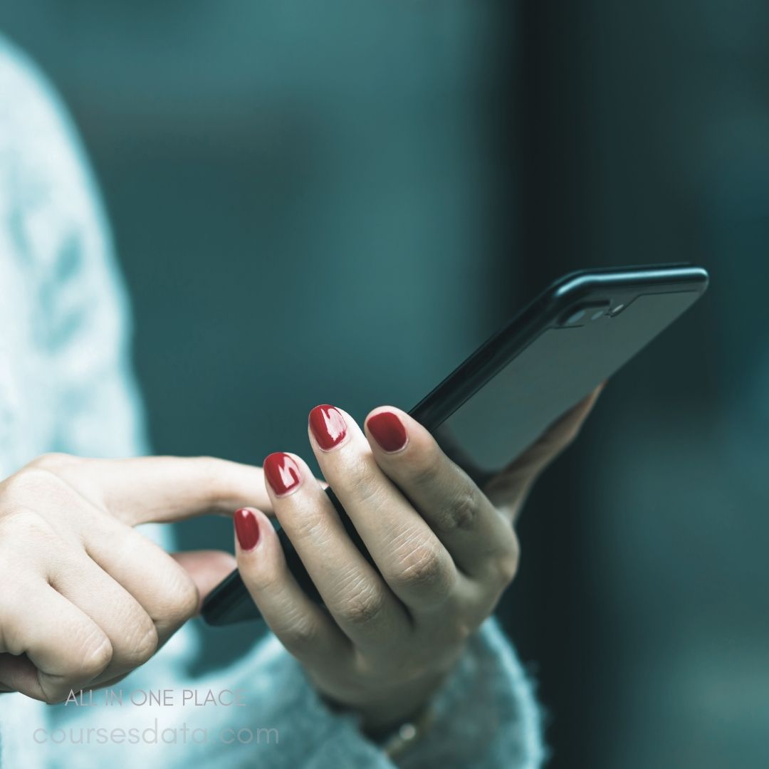 Woman holding smartphone, red nails.