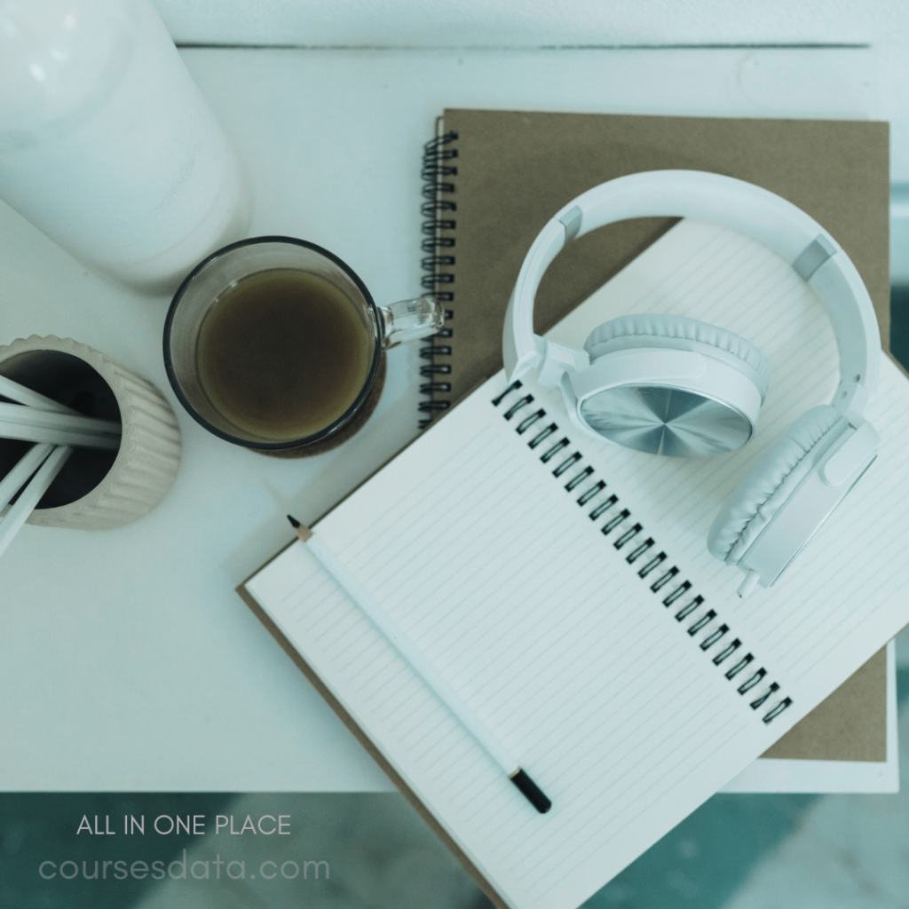 Coffee cup and headphones. Notebook with blank pages. Pencil resting on notebook. Mug on light surface. Stationery arranged neatly.