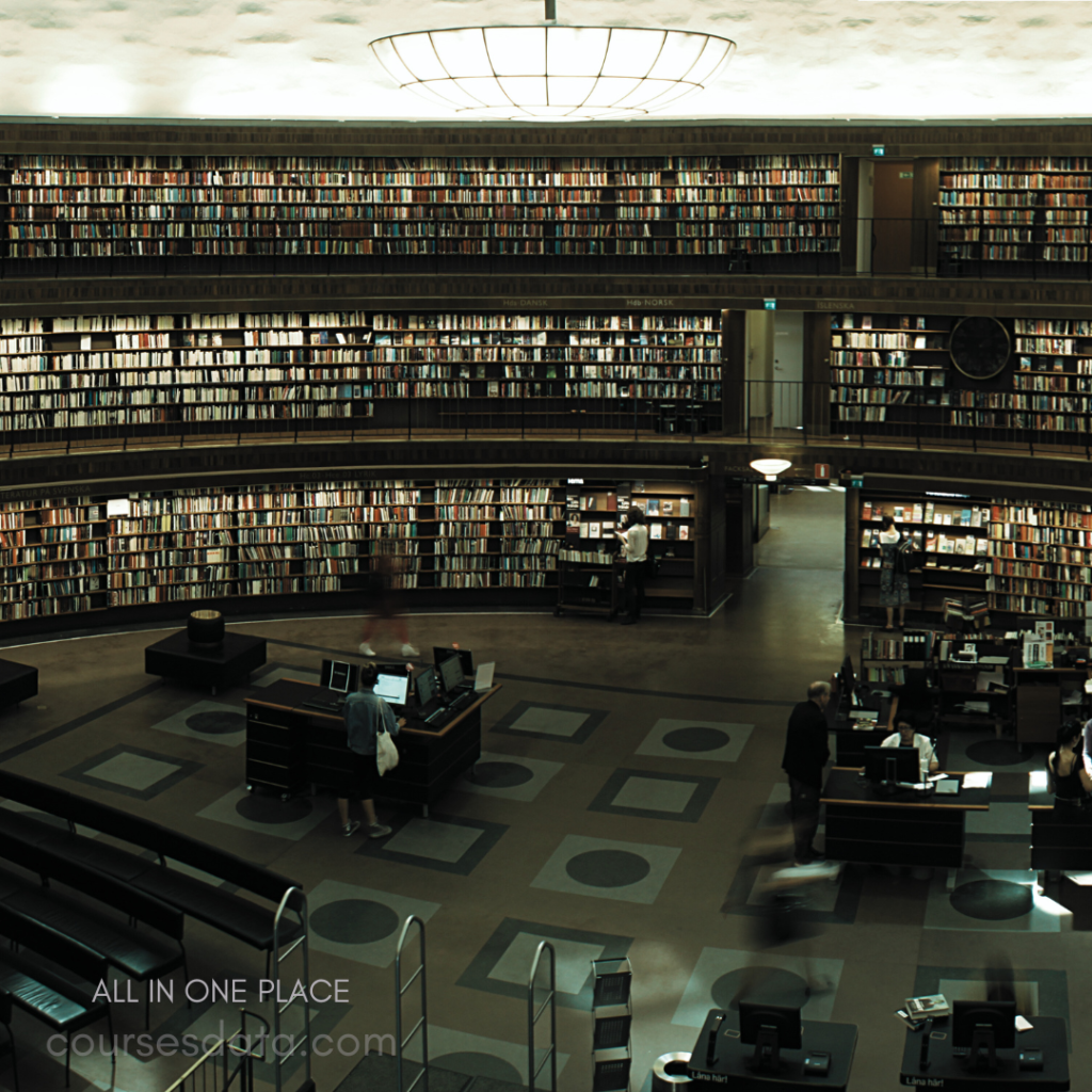 Spacious library interior. Rows of bookshelves. Central information desk. People browsing books. Soft overhead lighting.