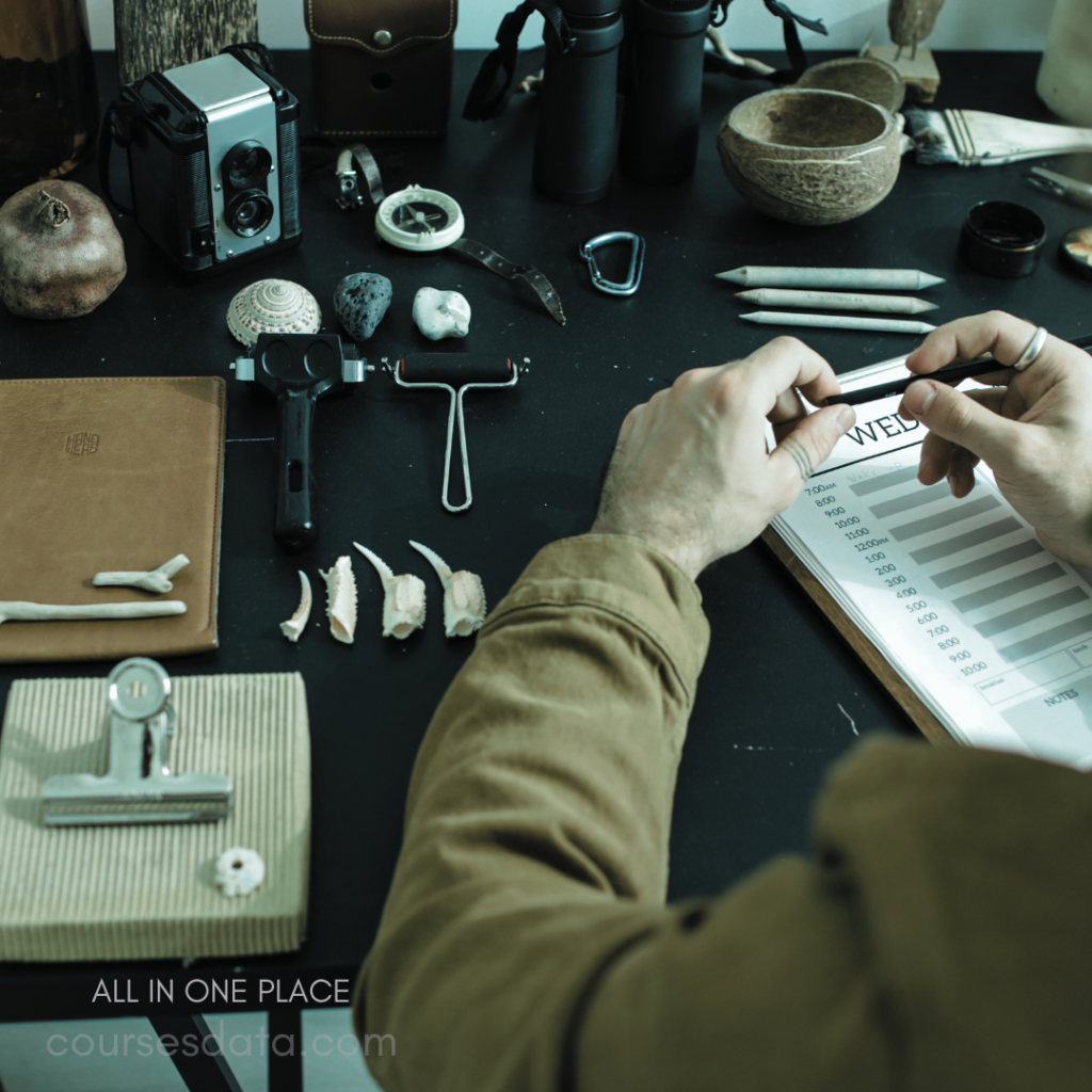 Hands holding pencil, sketching. Various tools and objects displayed. Camera, binoculars, and natural items. Notebook with graph, labeled "WELD." Workspace showcasing creative materials.