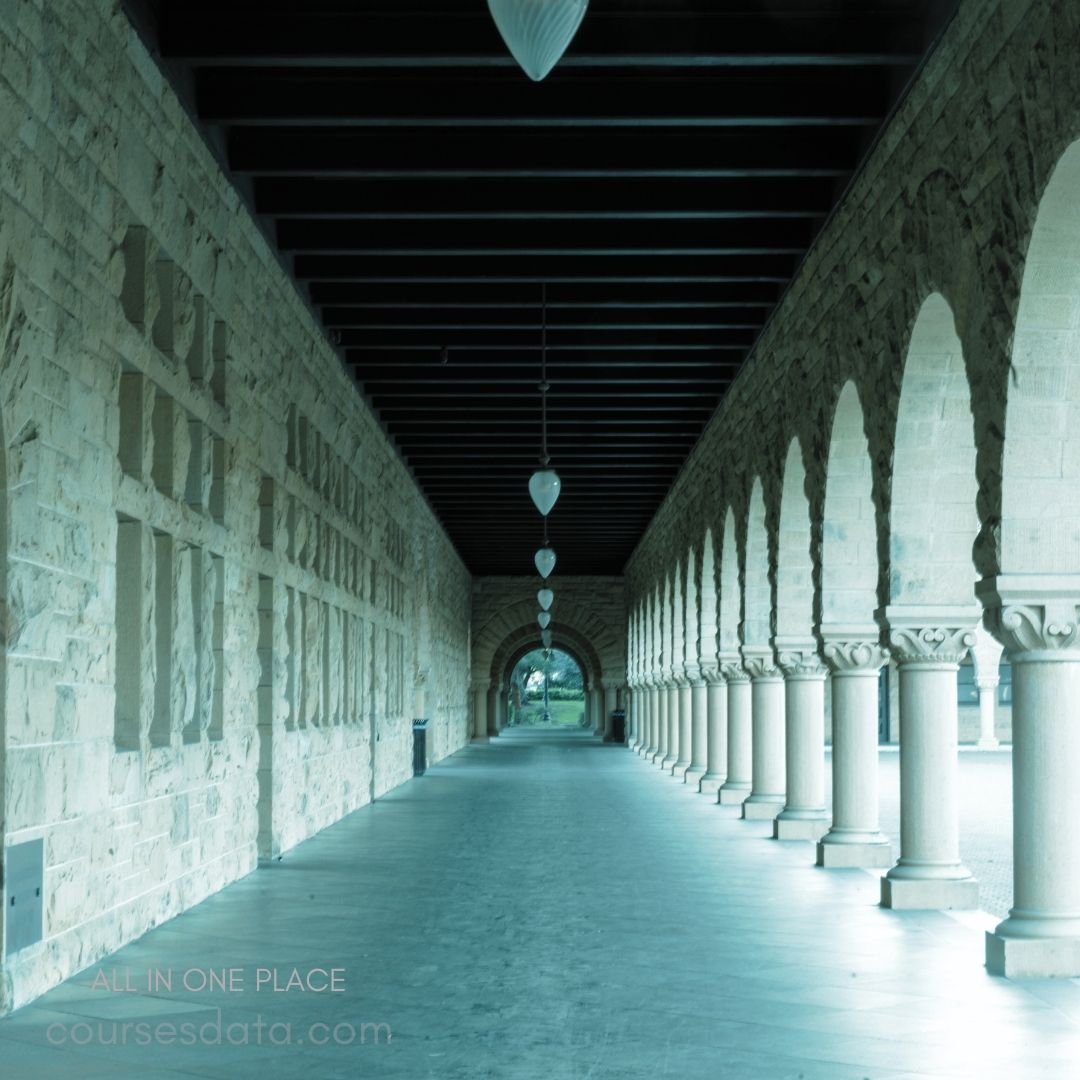 Stone archway corridor, columns, overhead lights.