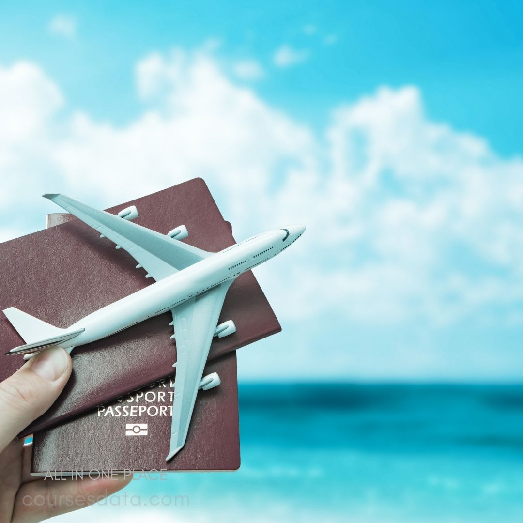 Airplane model on passports. Blue sky in background. Tropical beach setting. Hand holding items. Travel theme image.