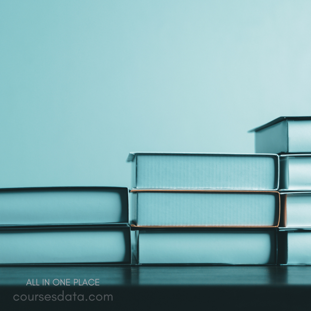 Stacked books on table. Muted blue background. Simple and organized display. Text visible at bottom.