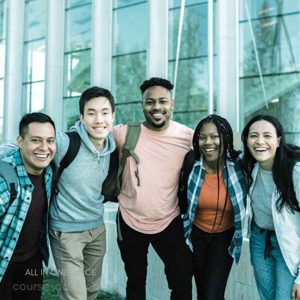 Group of diverse smiling friends. Standing together outside a building. Wearing casual attire and backpacks. Sunny day with bright reflections. Joyful expressions and camaraderie displayed.