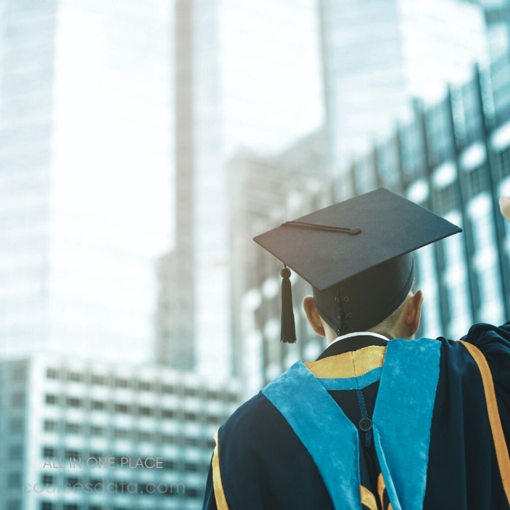 Graduating student in cap. Blue academic robe. Urban backdrop. Hand raised in celebration. Joyful moment captured.