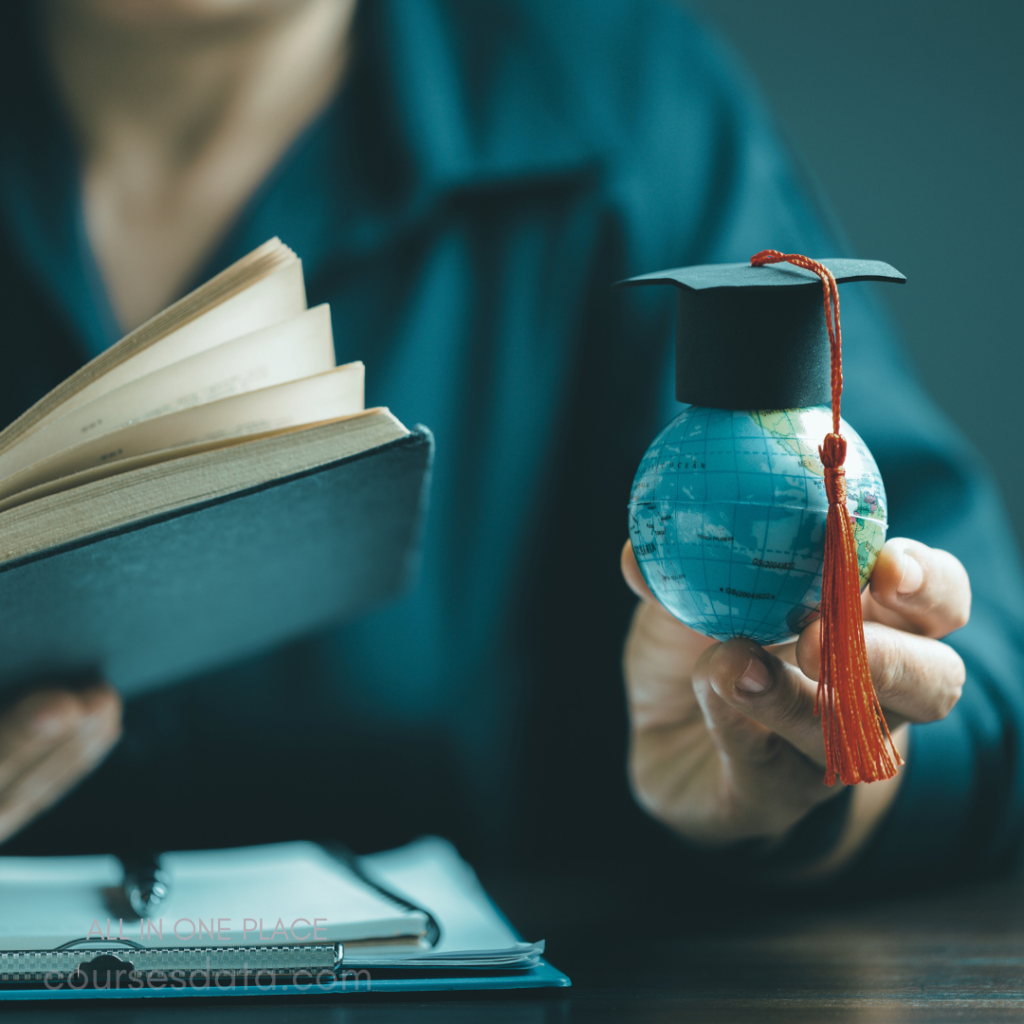 Person holding globe with cap. Open book in other hand. Dark background, focused lighting. Education and exploration themes. Desk with papers visible.