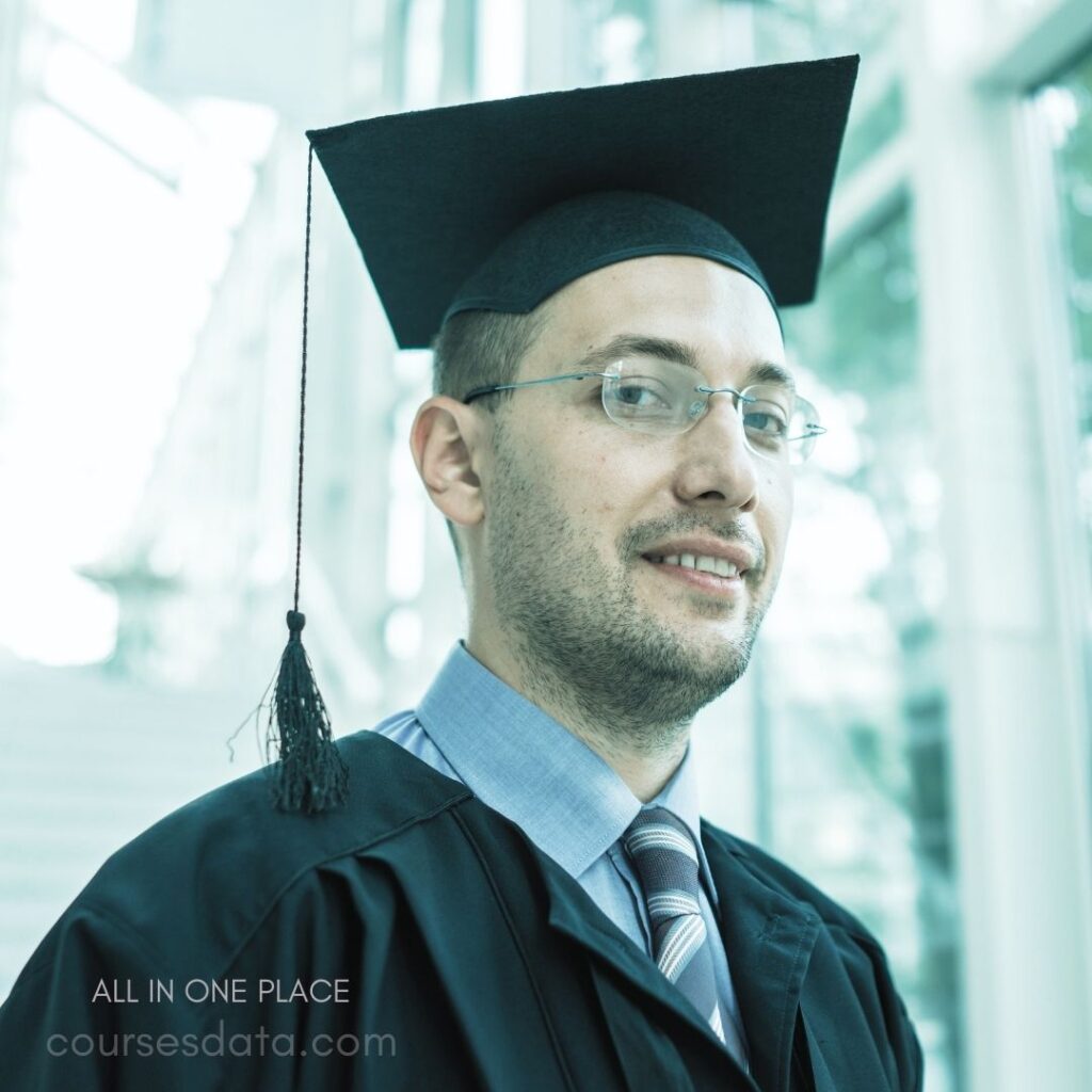 Graduating man in cap. Smiling against glass background. Wearing black robe and tie. Casual academic celebration moment. Stylish glasses and light shirt.