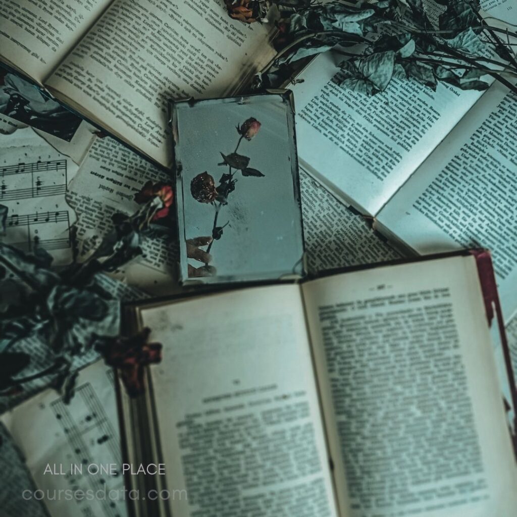 Books and dried roses scattered. Small mirror reflecting a flower. Muted colors create a vintage feel. Sheet music partially visible underneath. All arranged in artistic disarray.