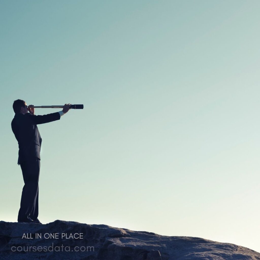 Man in suit with telescope. Standing on rocky ledge. Clear blue sky background. Exploring distant horizons. Professional and contemplative stance.