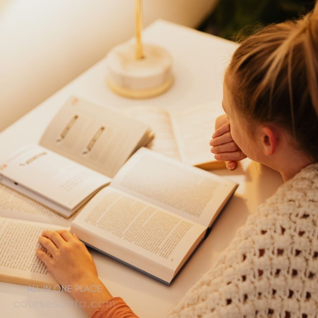 Person reading books at desk.