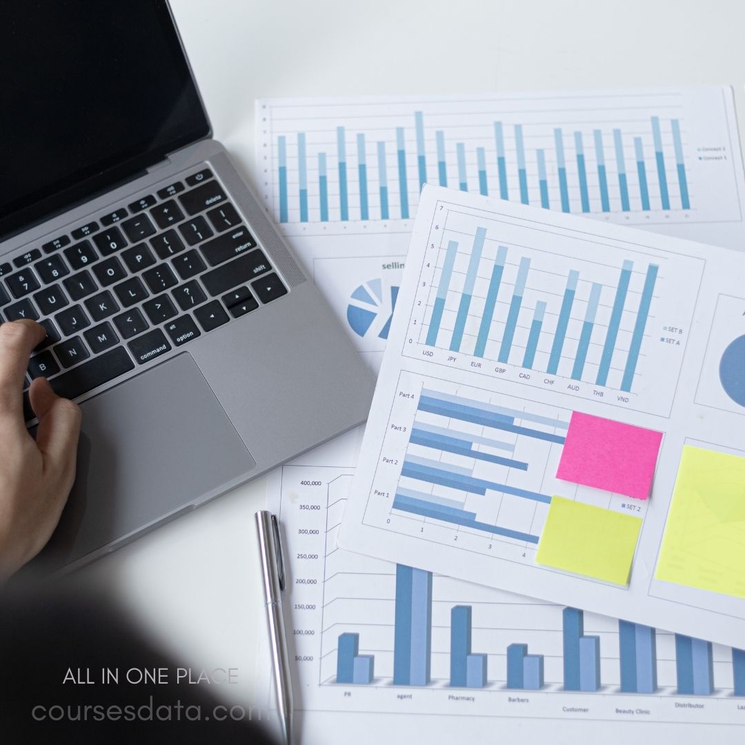Laptop surrounded by data charts.