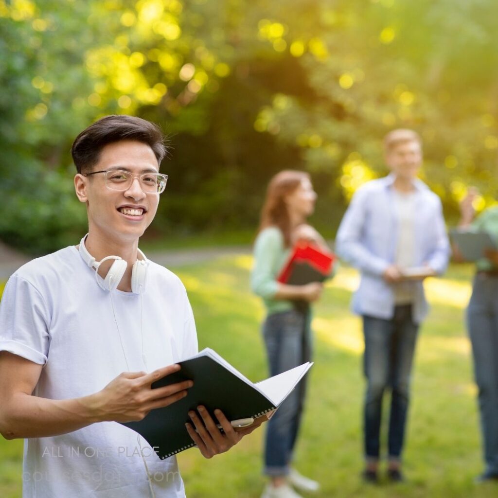 Smiling student with notebooks outdoors.