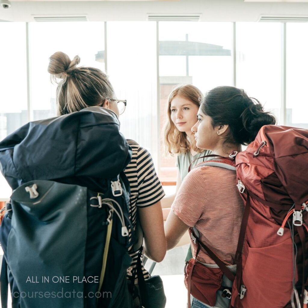 Three women with backpacks conversing.