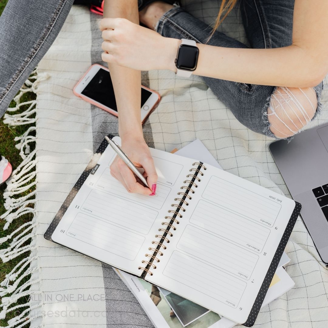 Person writing in planner outdoors.