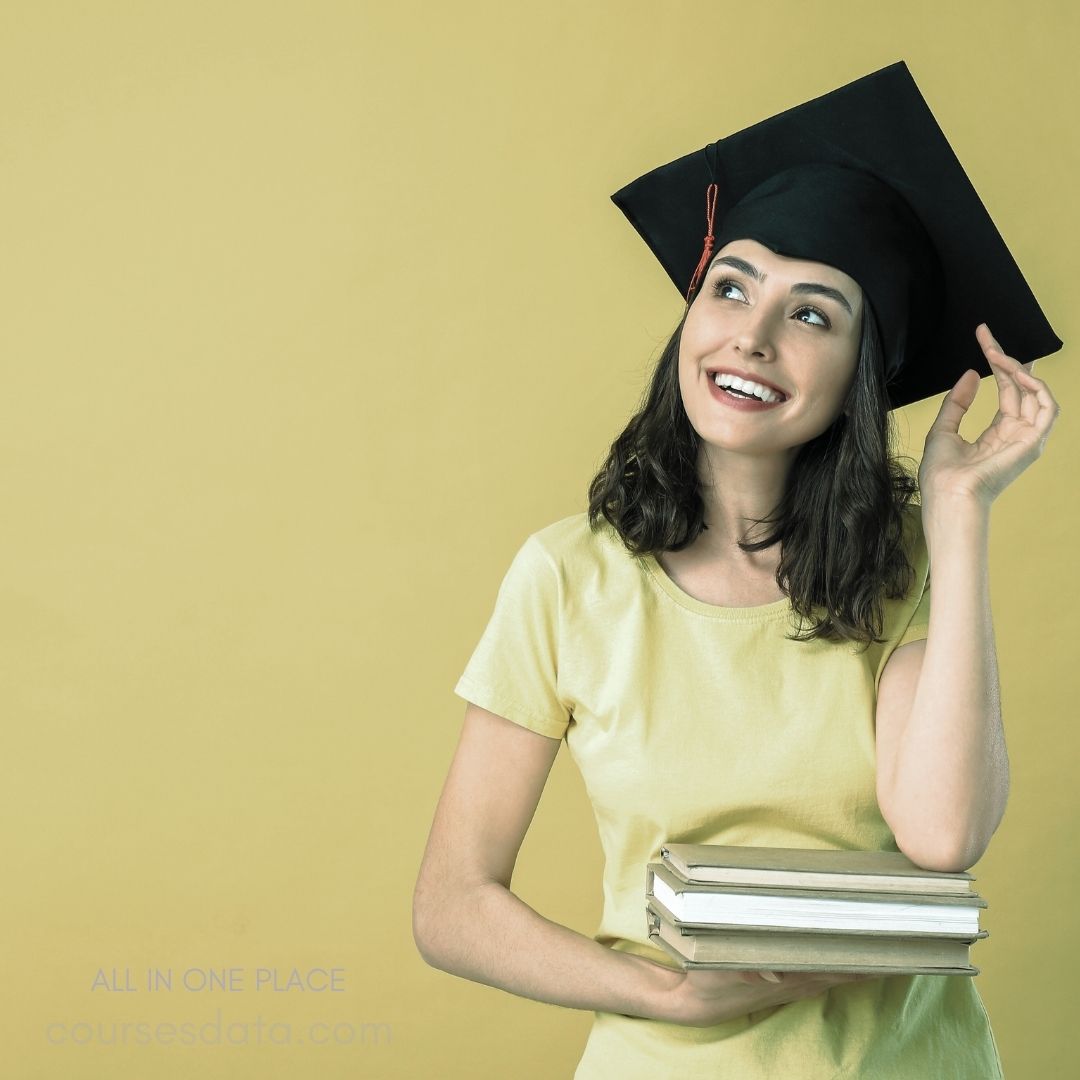 Smiling graduate holding books.