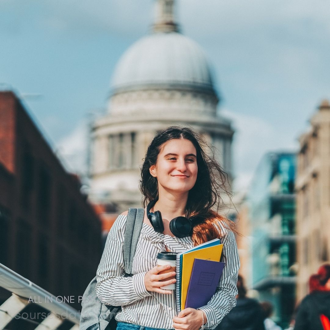 Smiling student with books, headphones.