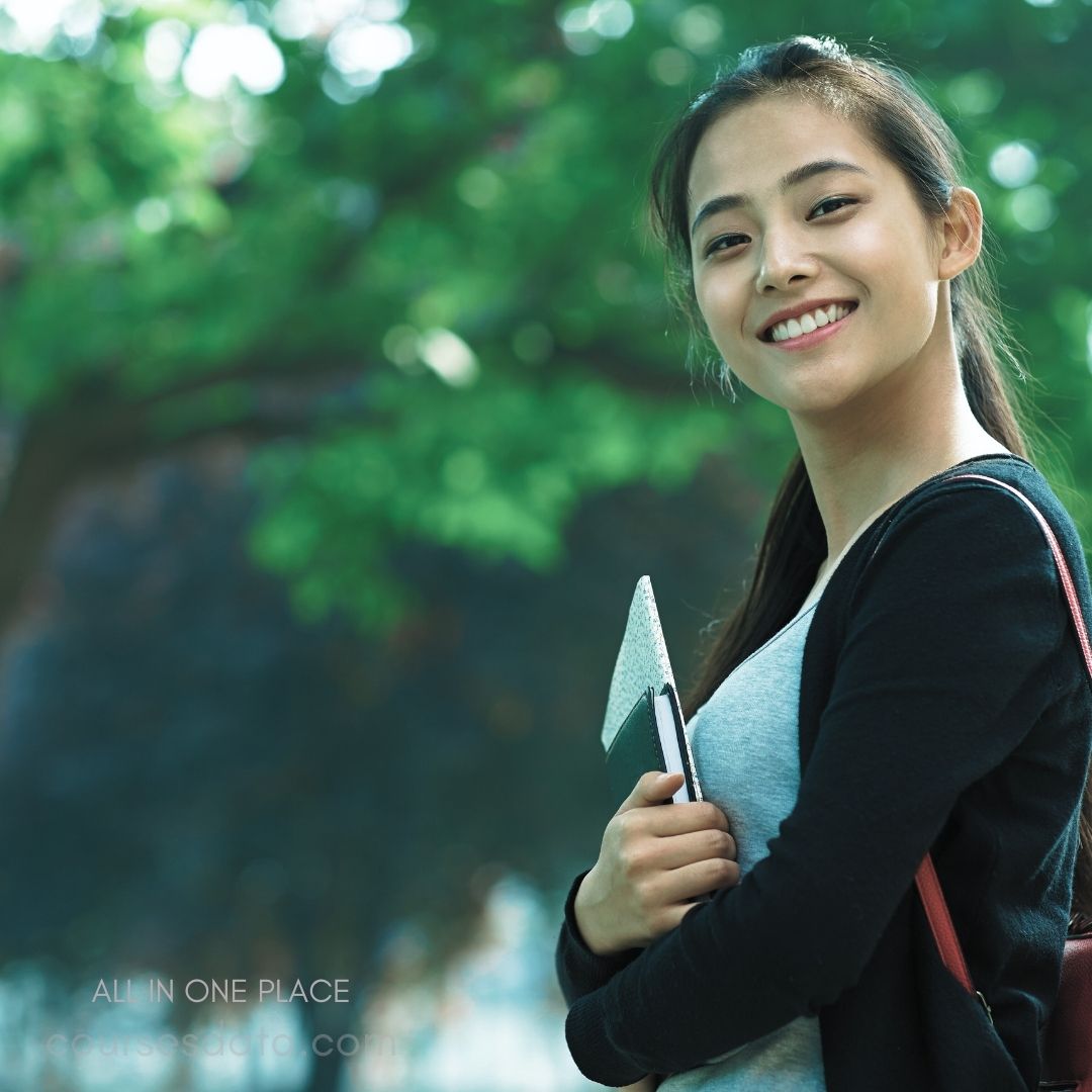 Smiling young woman holding notebook.