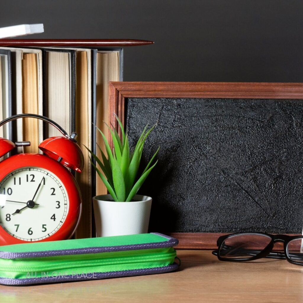 Desk with clock, books, plant.