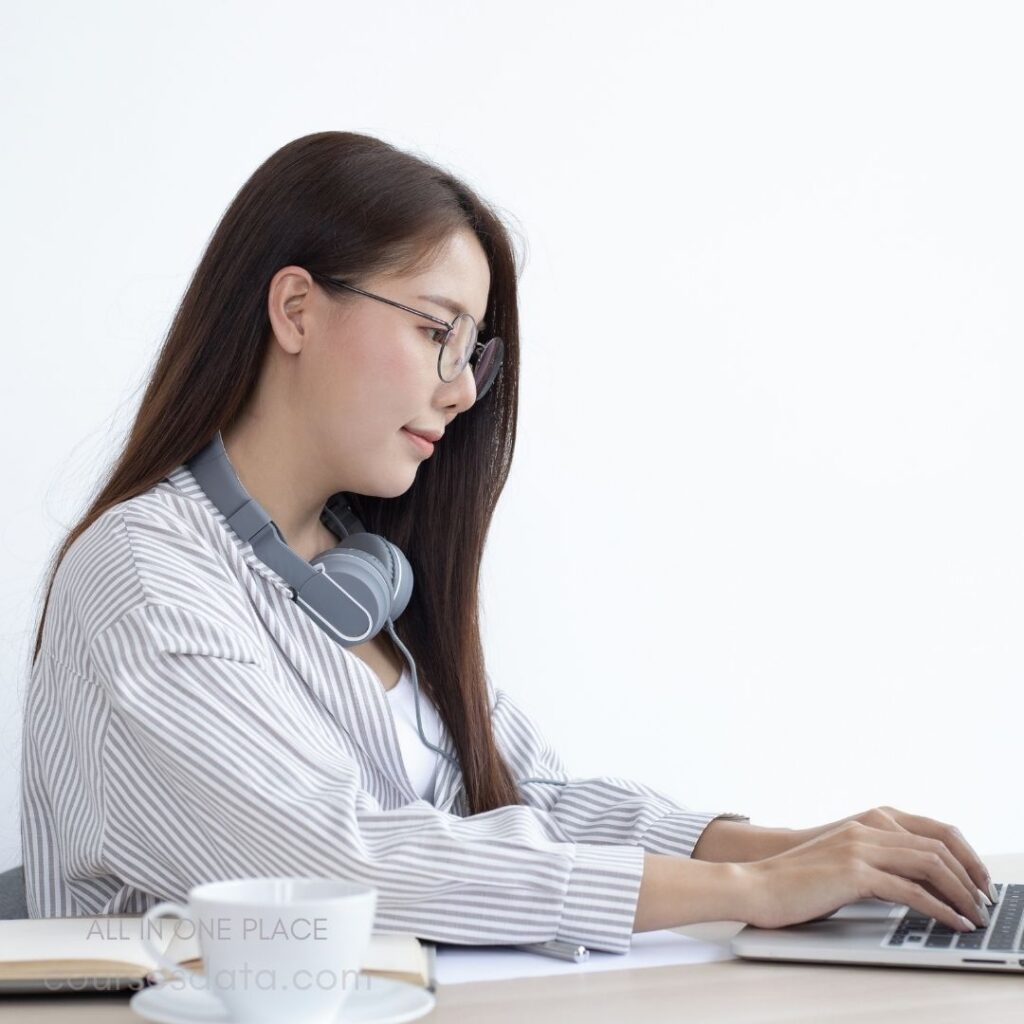 Woman working on laptop, headphones.