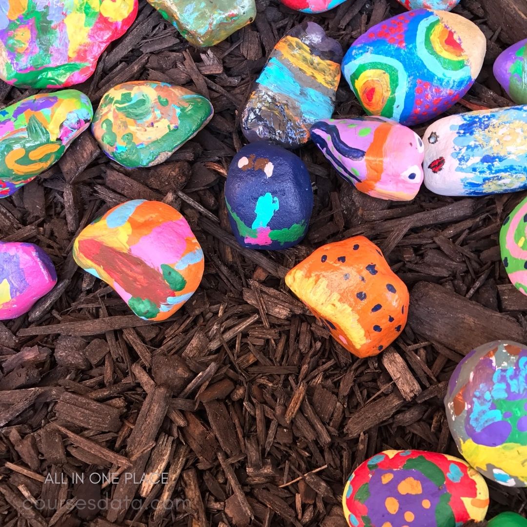Colorfully painted rocks, mulch background.
