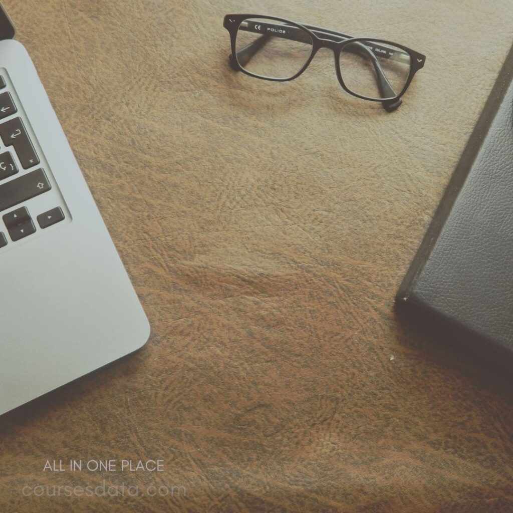 Laptop, glasses, notebook on table.