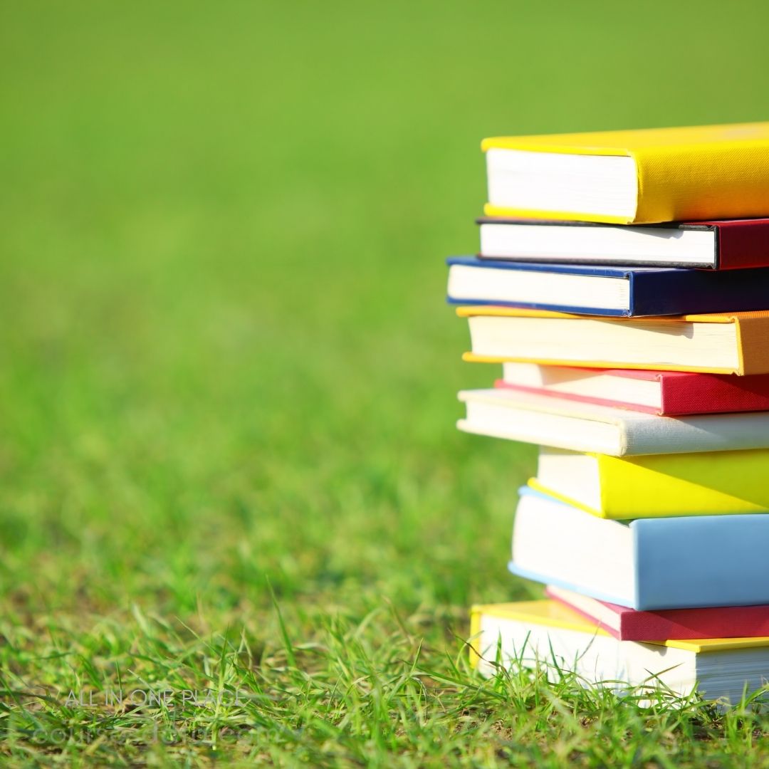 Stack of colorful books on grass.