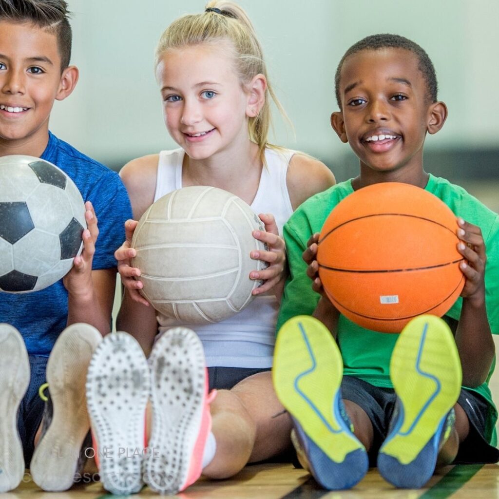 Children smiling with various sports balls.