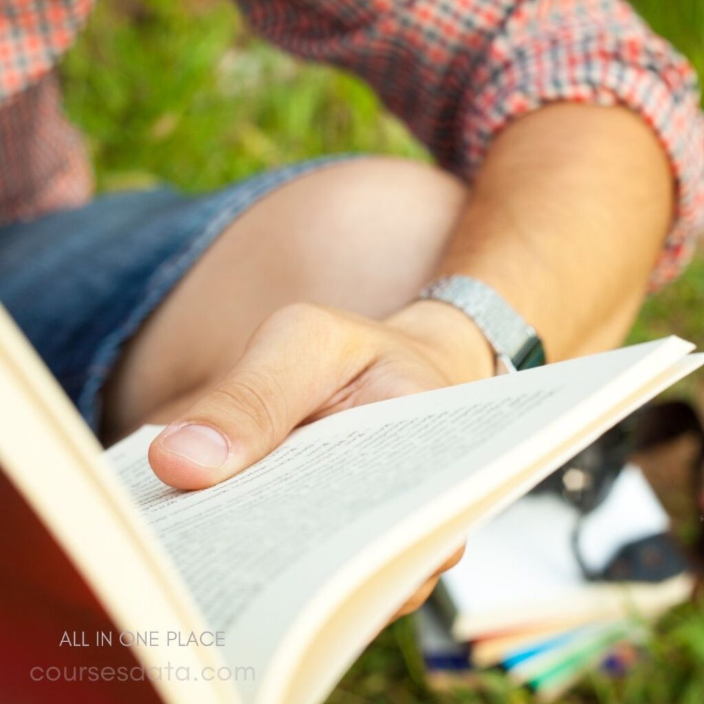 Person reading book outdoors.