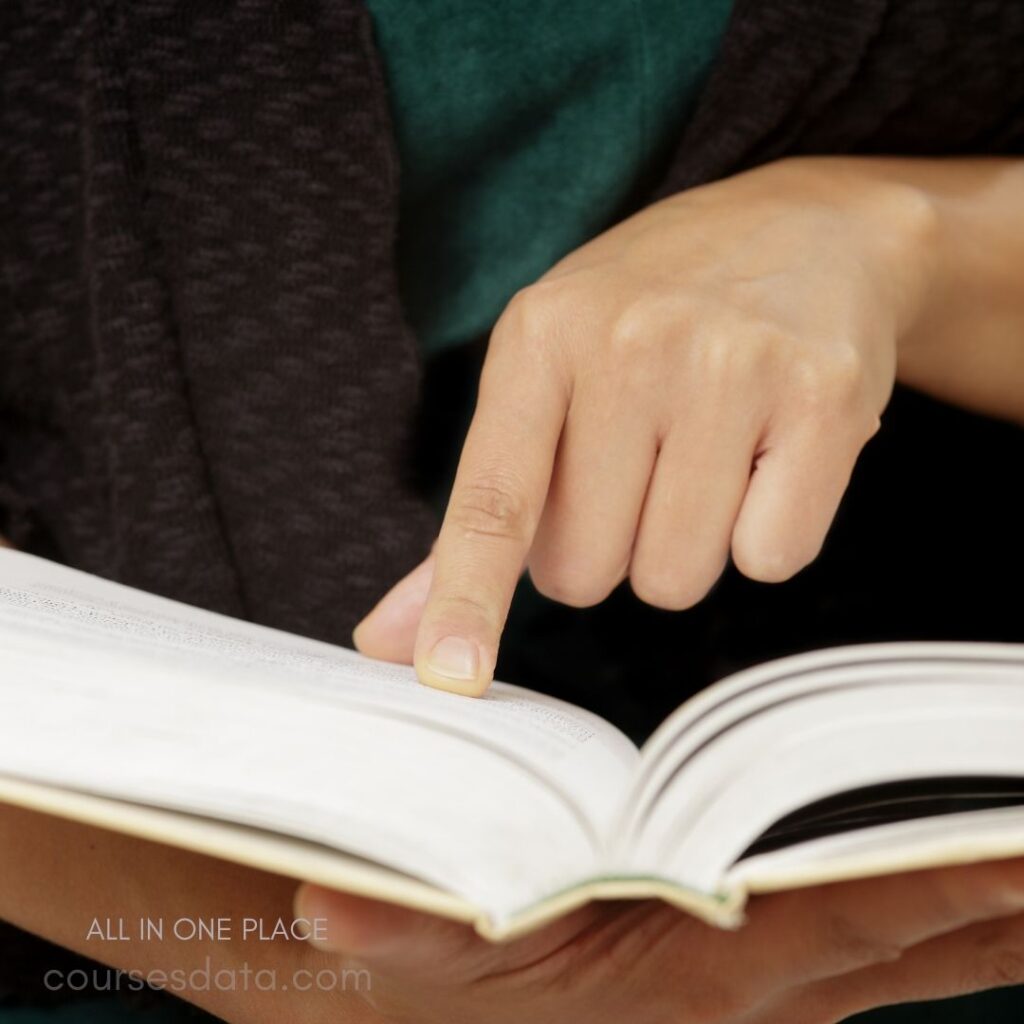 Person pointing at open book.