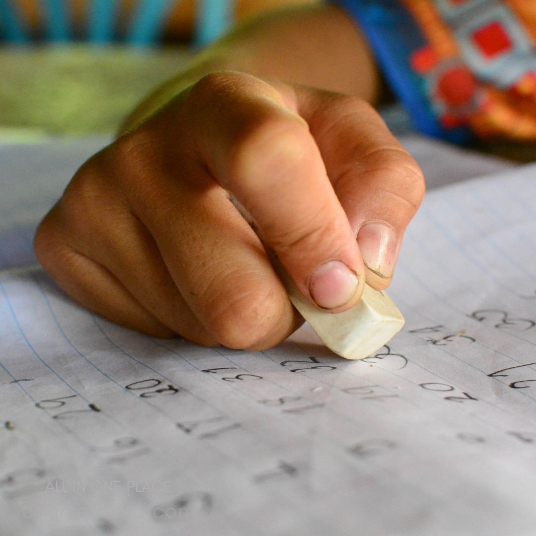 Hand erasing numbers from paper.