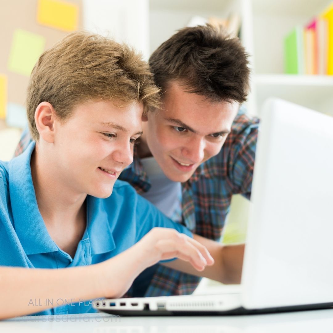 Two young men engaged with laptop.