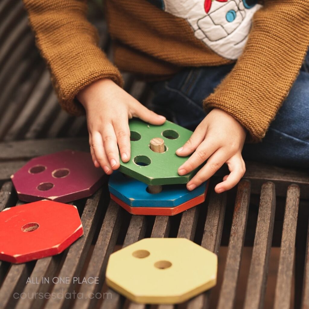 Child stacking colorful wooden shapes.