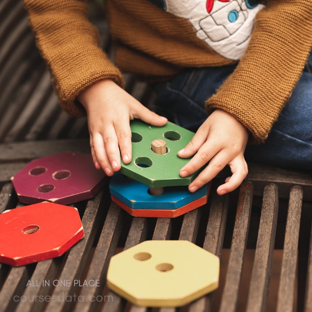 Child stacking colorful wooden shapes.