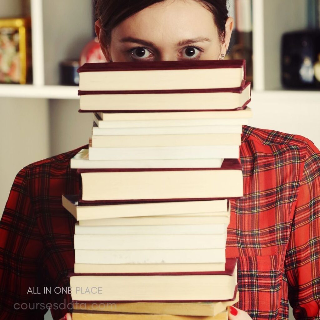 Person hiding behind stacked books.