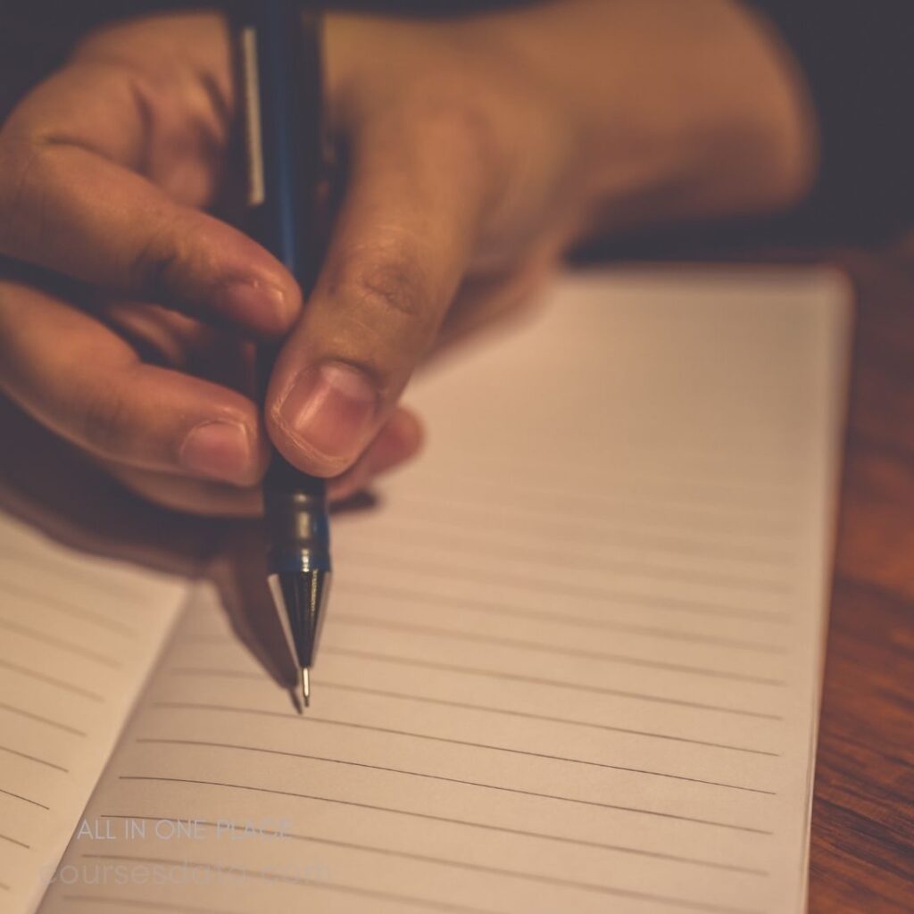 Hand holding pen over notebook.