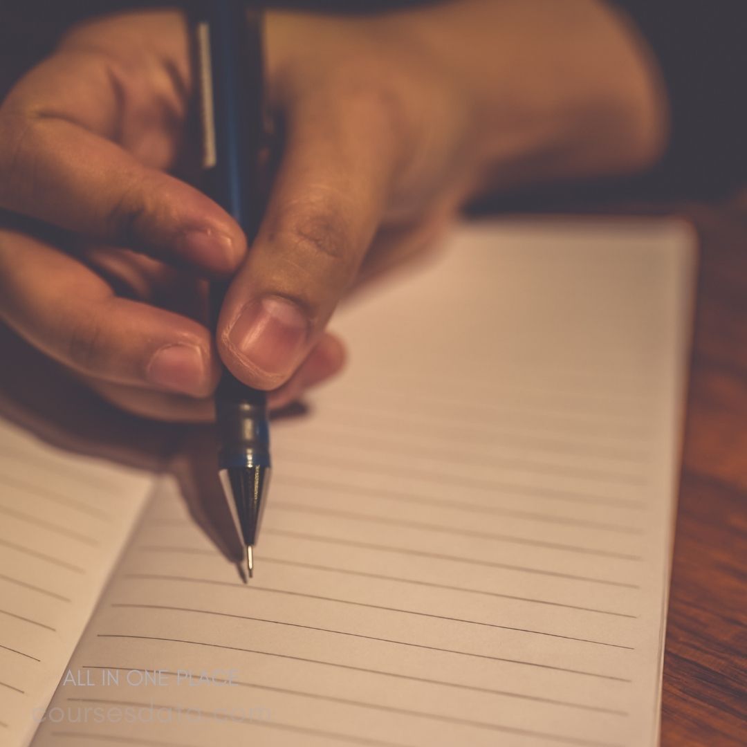 Hand holding pen over notebook.