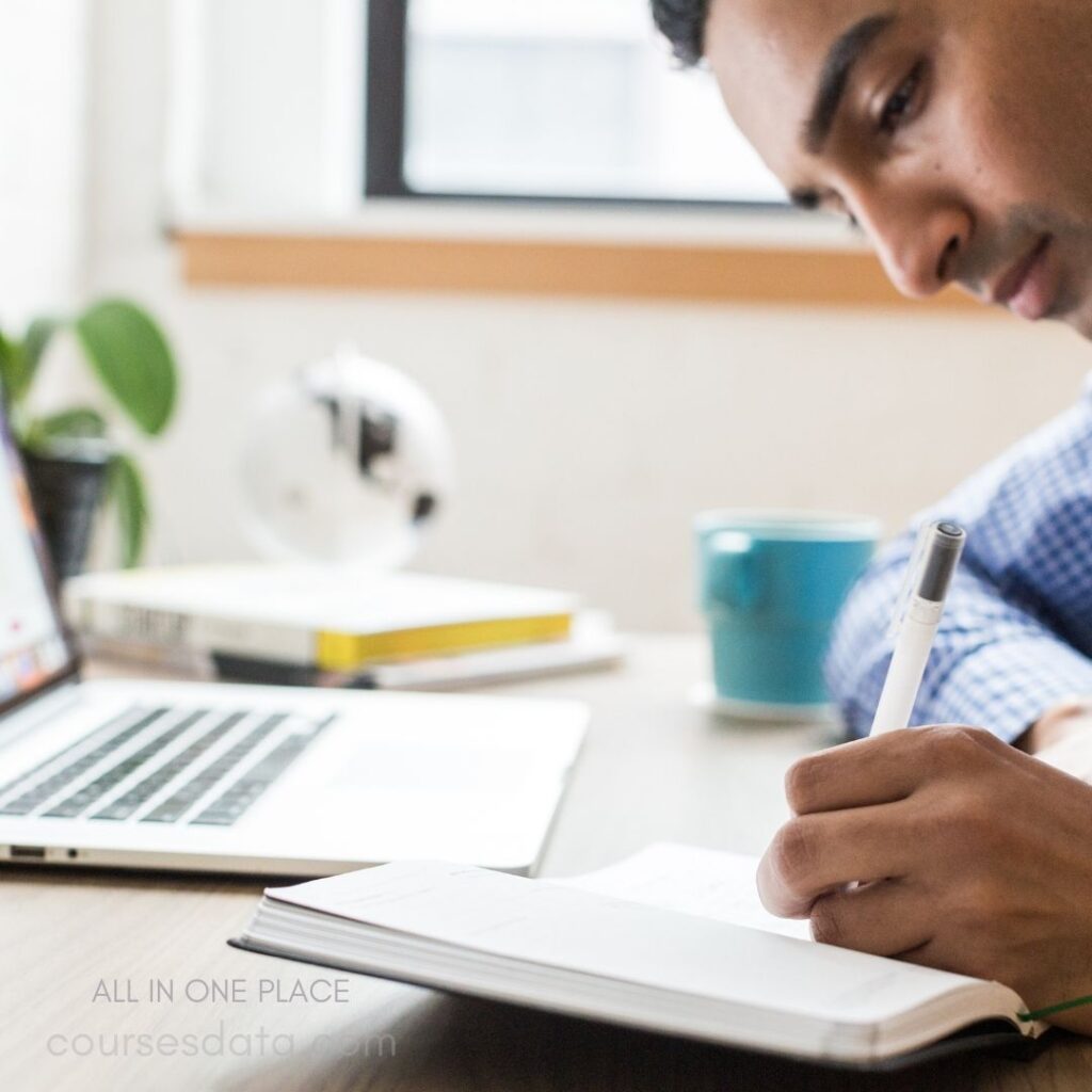 Man writing in notebook, focused.