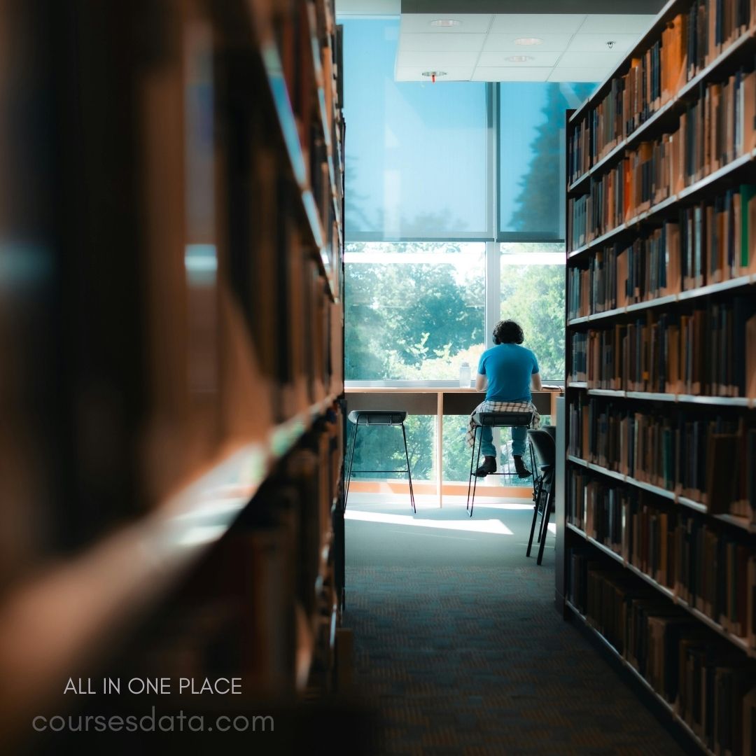 Person studying in library aisle.