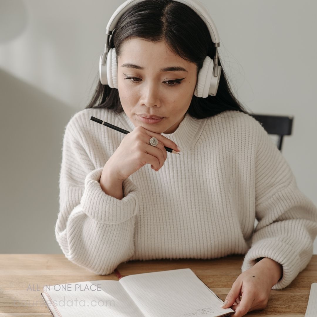 Woman in headphones, thoughtful, notebook.