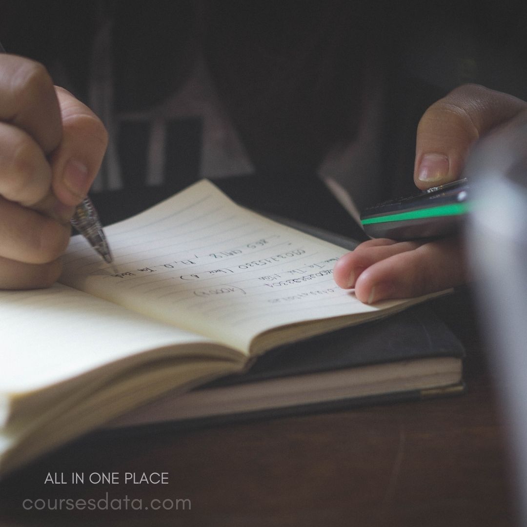 Writing notes with smartphone nearby.