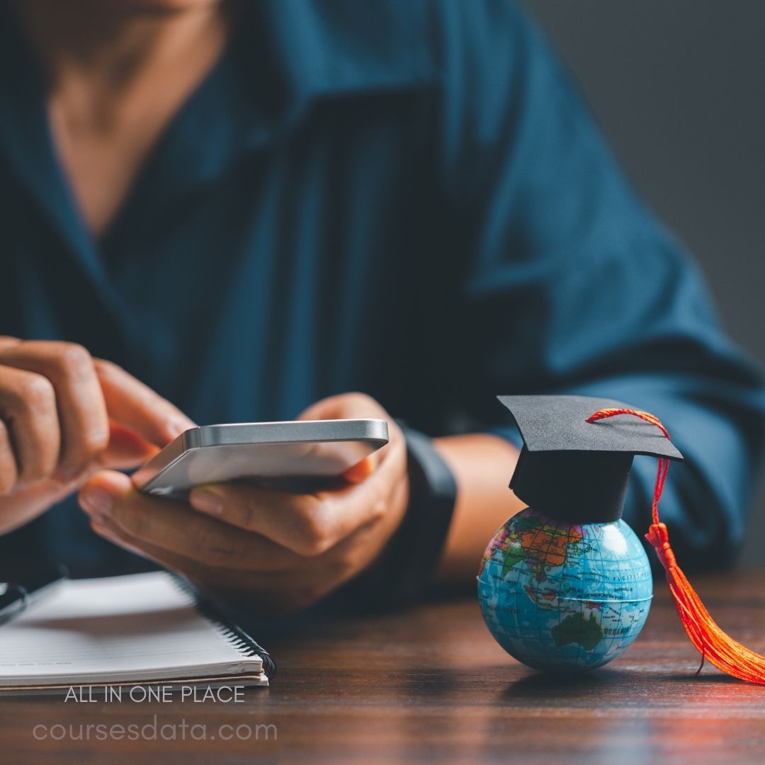 Student using smartphone beside globe.