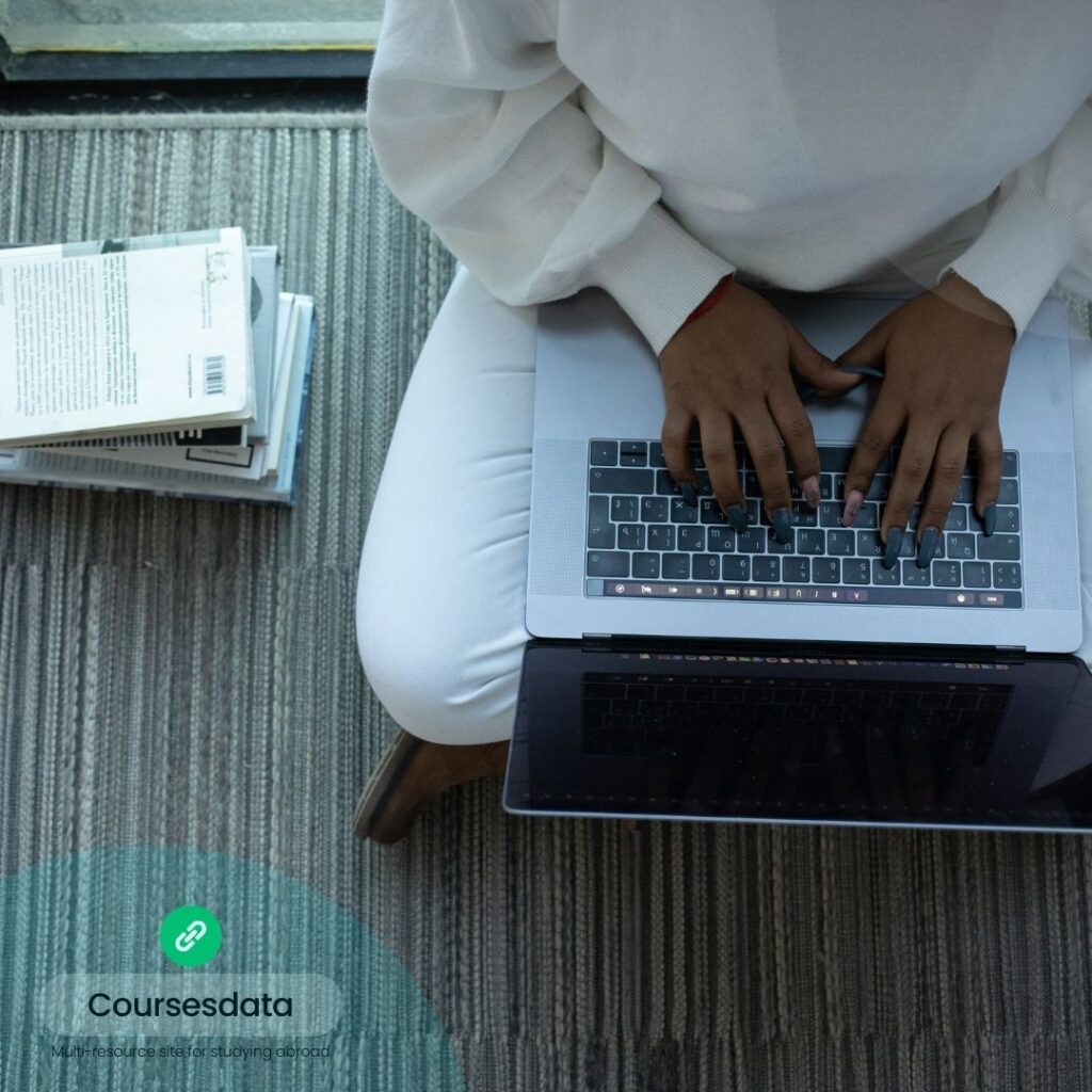 Person typing on laptop, books nearby.