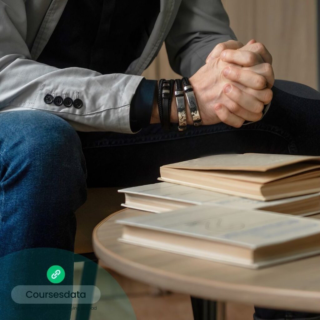 Person's hands clasped, books nearby.