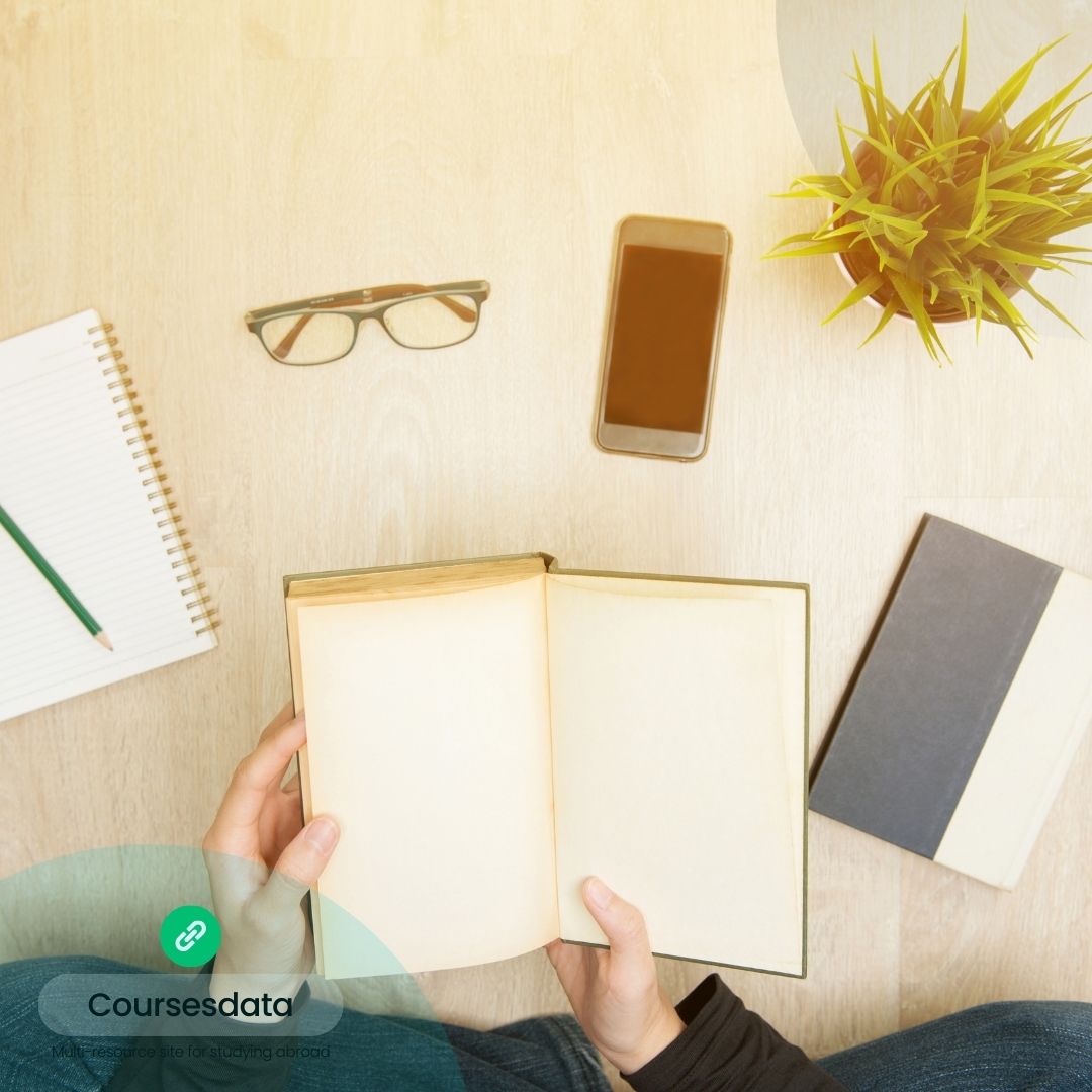 Open book, glasses, phone, plant.