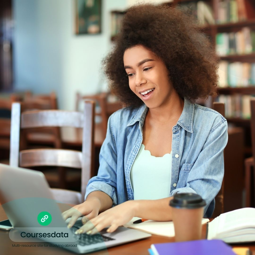 Smiling student using laptop, studying.