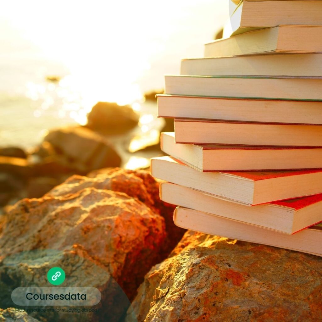 Books stacked on rocky shoreline.