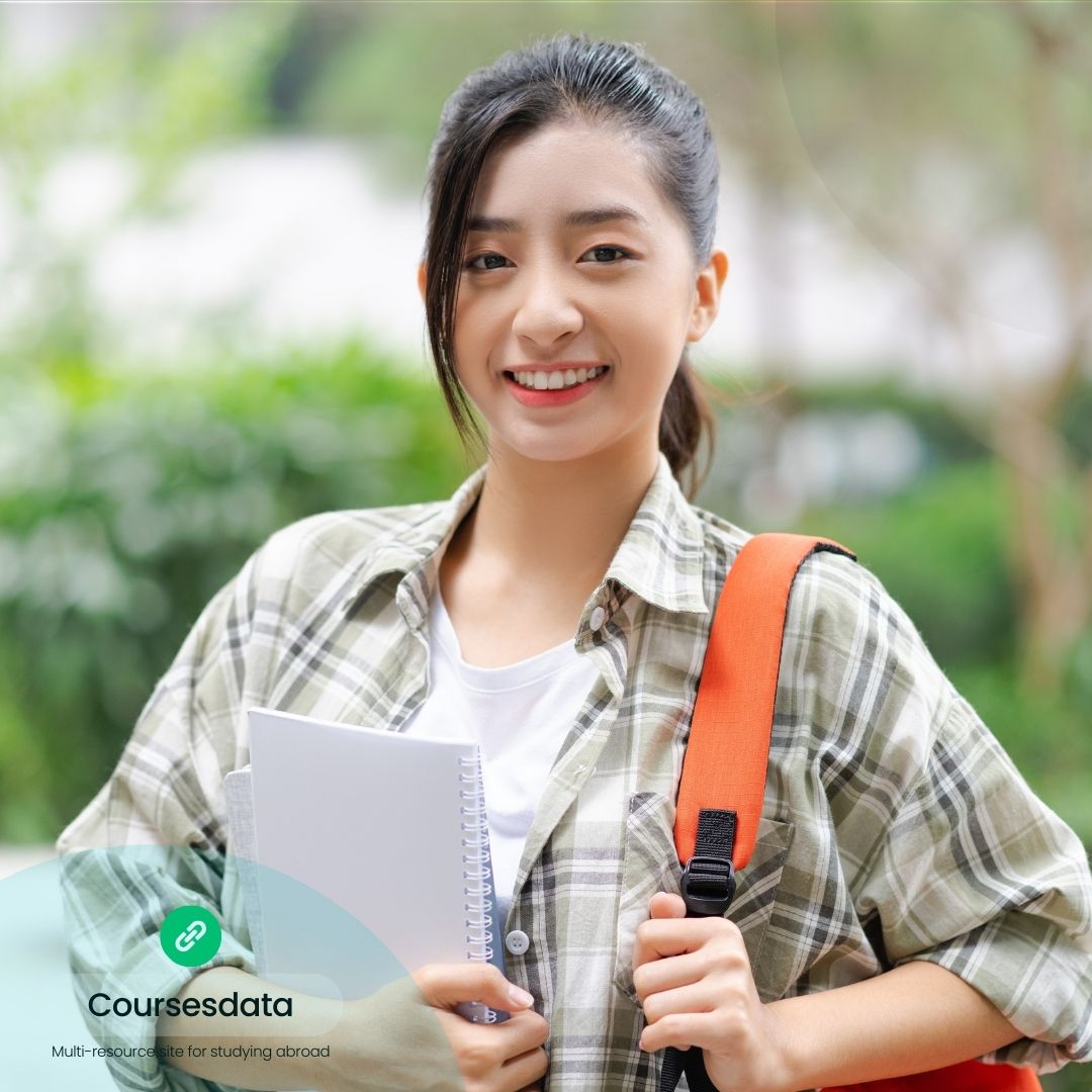 Smiling student holding notebooks.