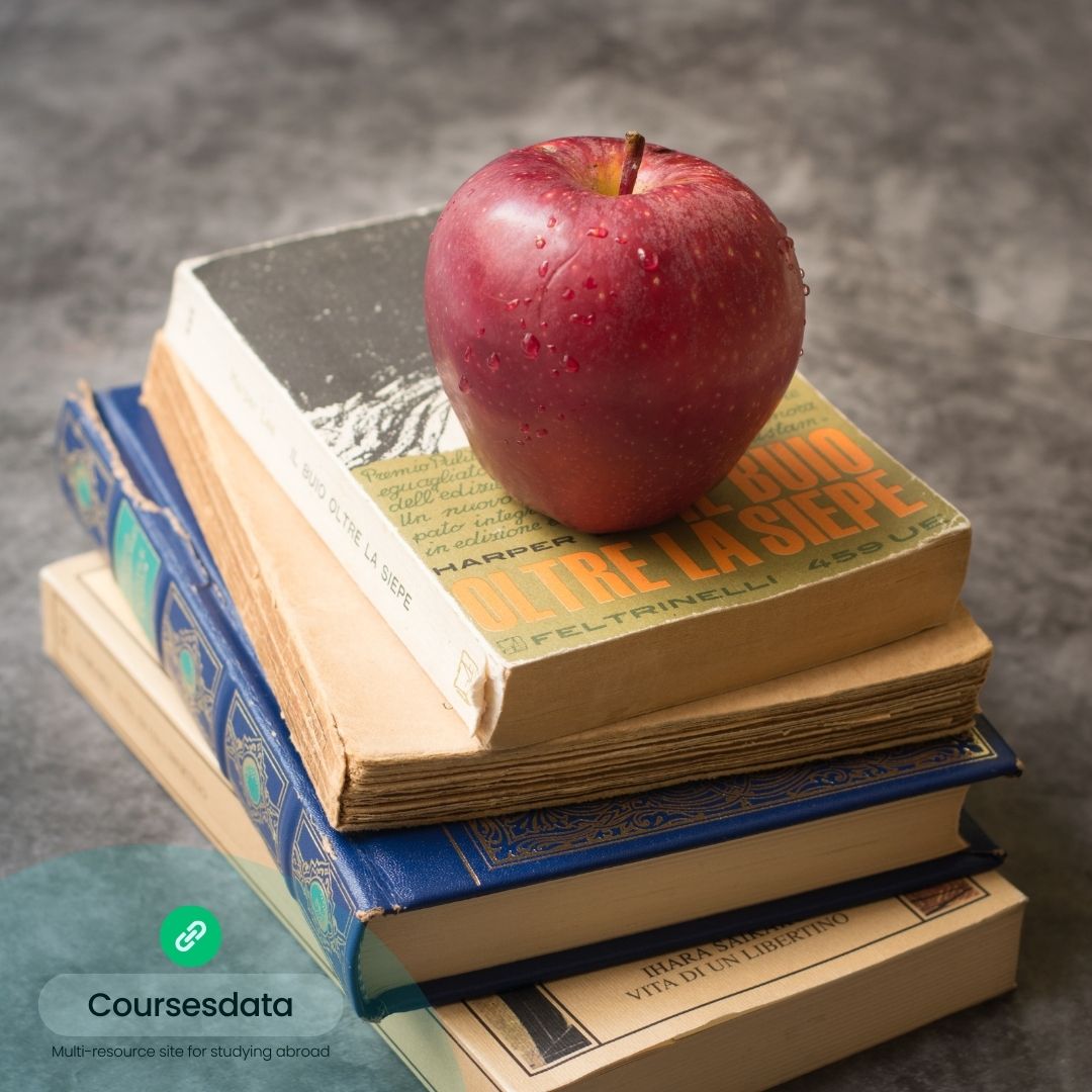 Red apple atop stacked books.