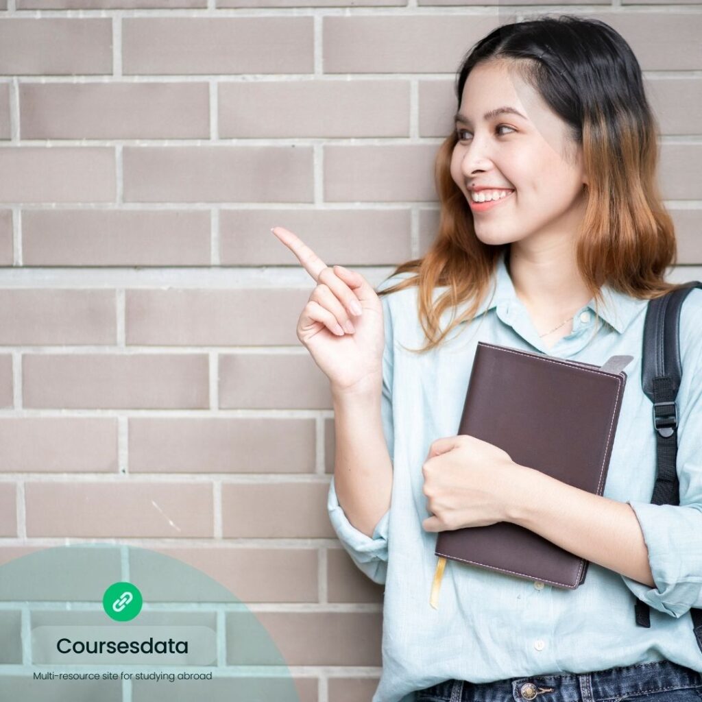 Smiling woman with notebook, pointing.