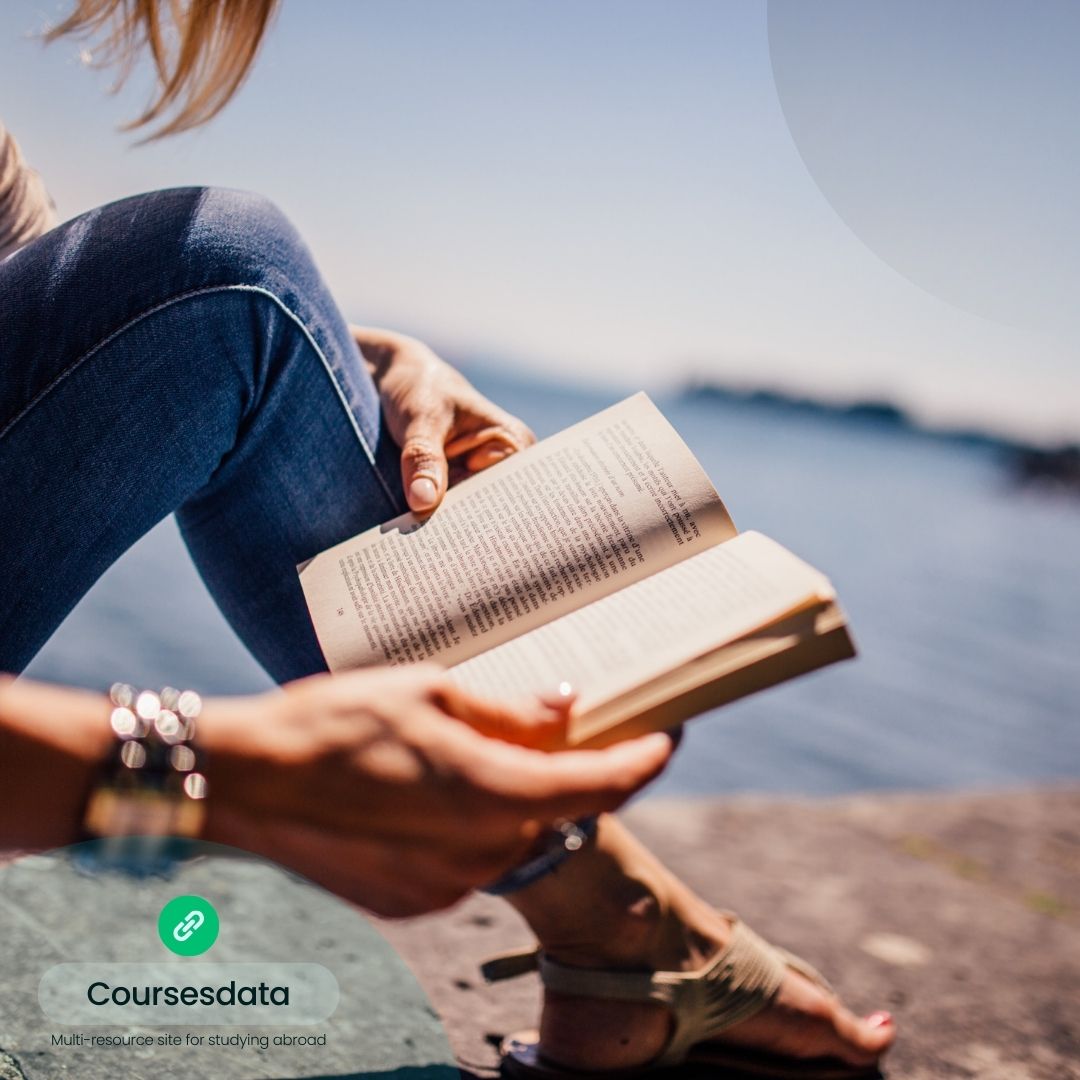 Person reading book by water.